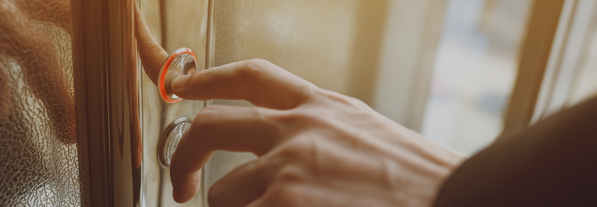 Close-up of a hand pressing a lit-up elevator button inside a modern elevator, as if seeking immediate assistance from injury lawyers. The button has a red glow indicating it has been activated. The background is softly blurred, focusing on the action of pressing the button; elevator accident attorneys concept image