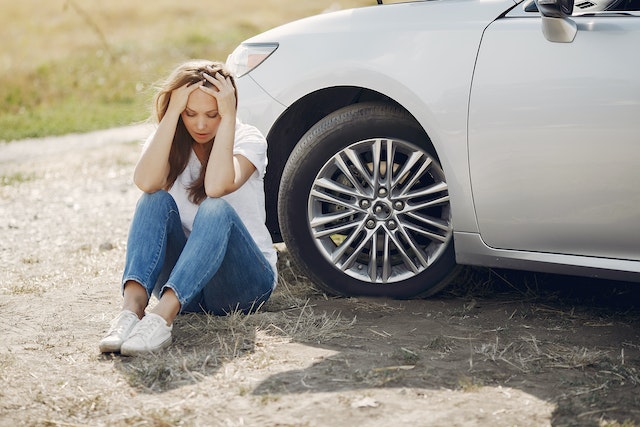 woman sitting next to car