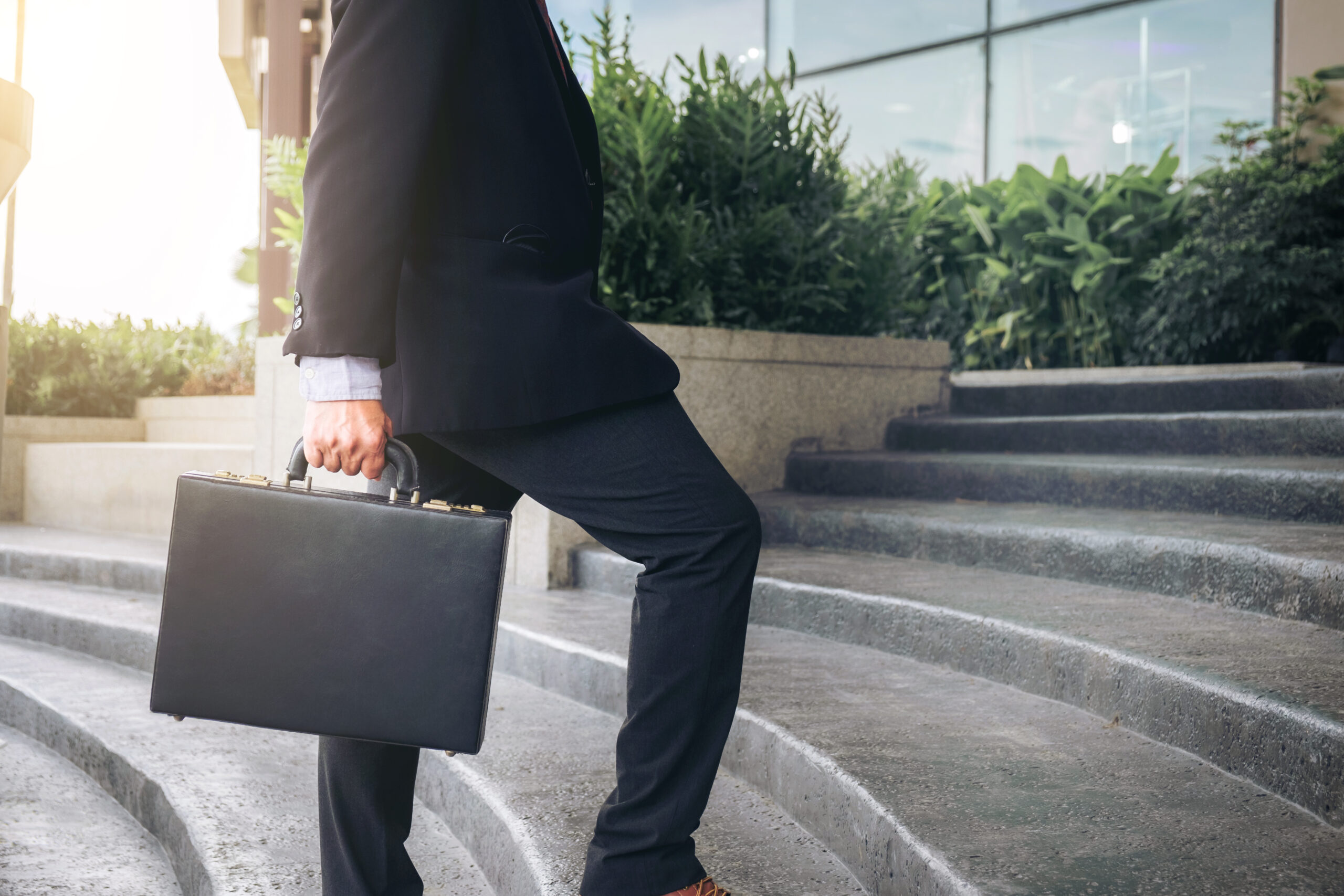 Businessman walking up the stairs and holding a briefcase in hand working with confidence